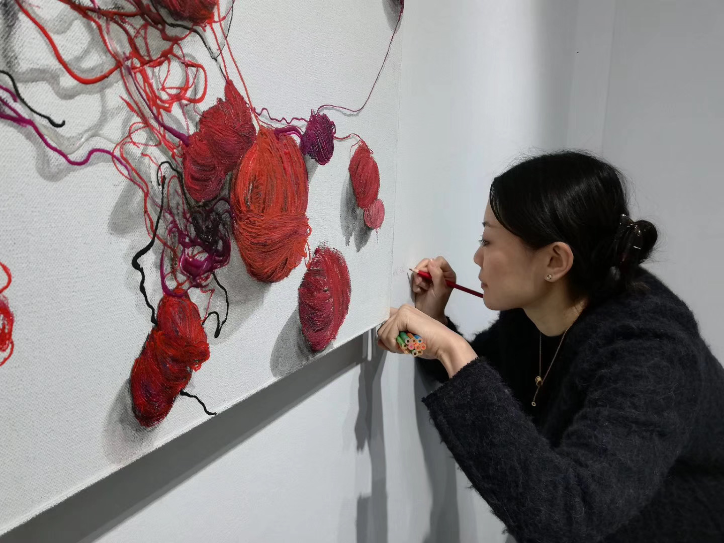 Yutong Zhao working closely on a red wool relief painting